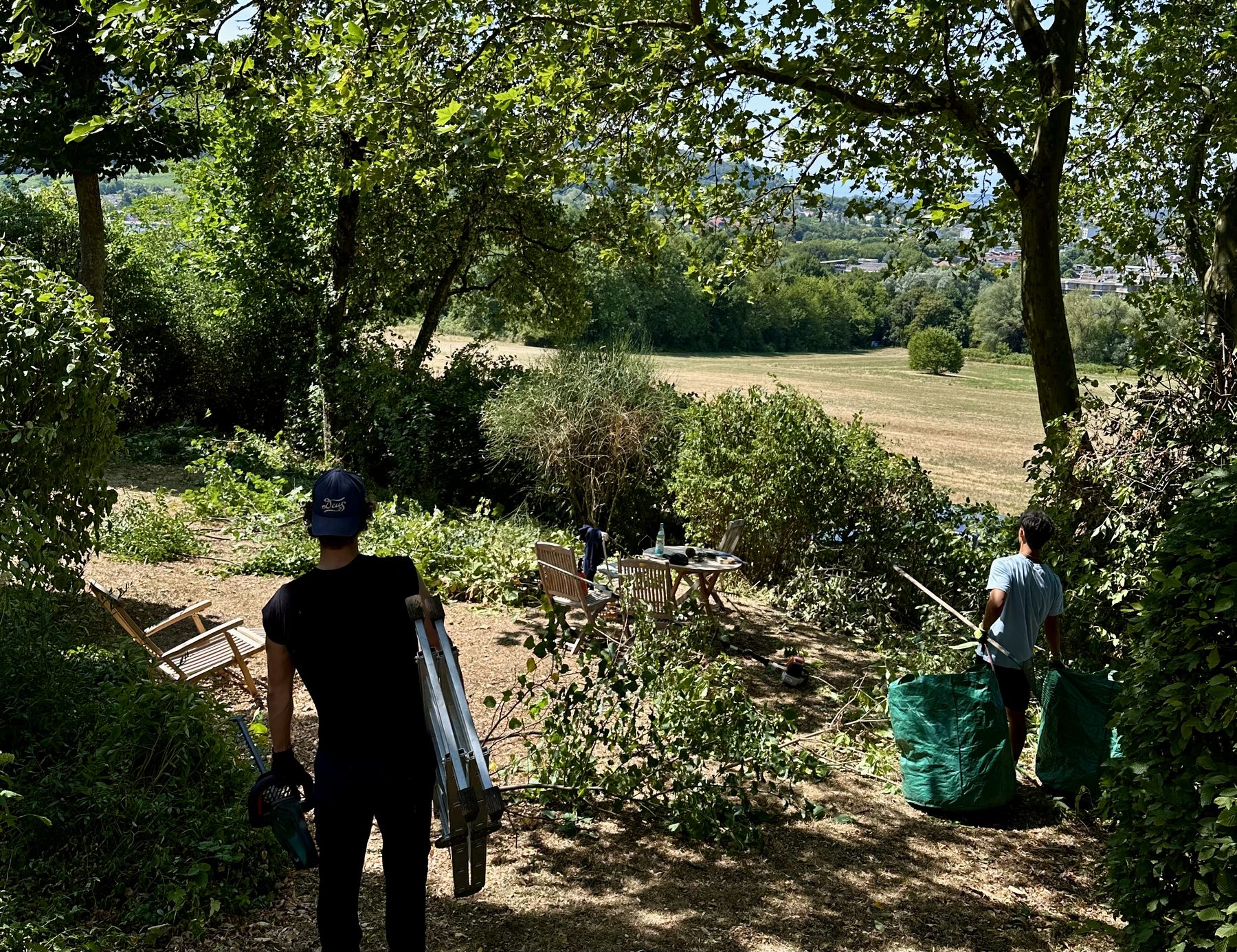 Zwei Studierende bei Gartenarbeiten mit Blick über die Landschaft