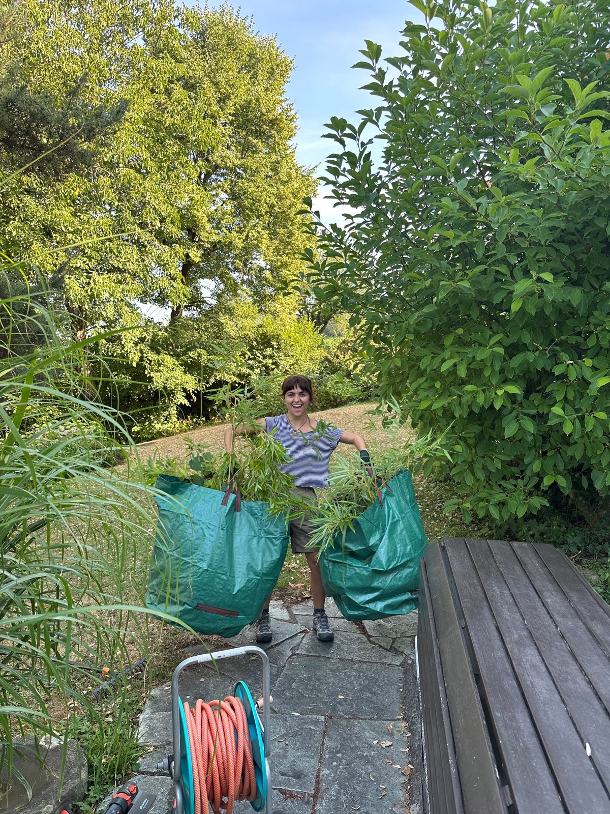 Studentin mit gebündeltem Grünabfall in Gartensäcken